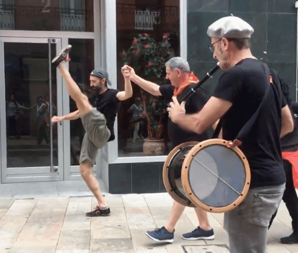 Hombres bailando y tocando tambores en la calle.