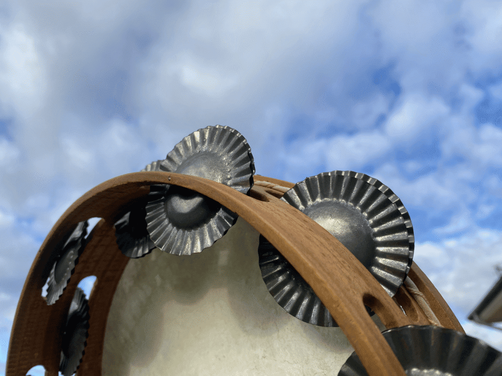 Pandereta bajo cielo azul con nubes